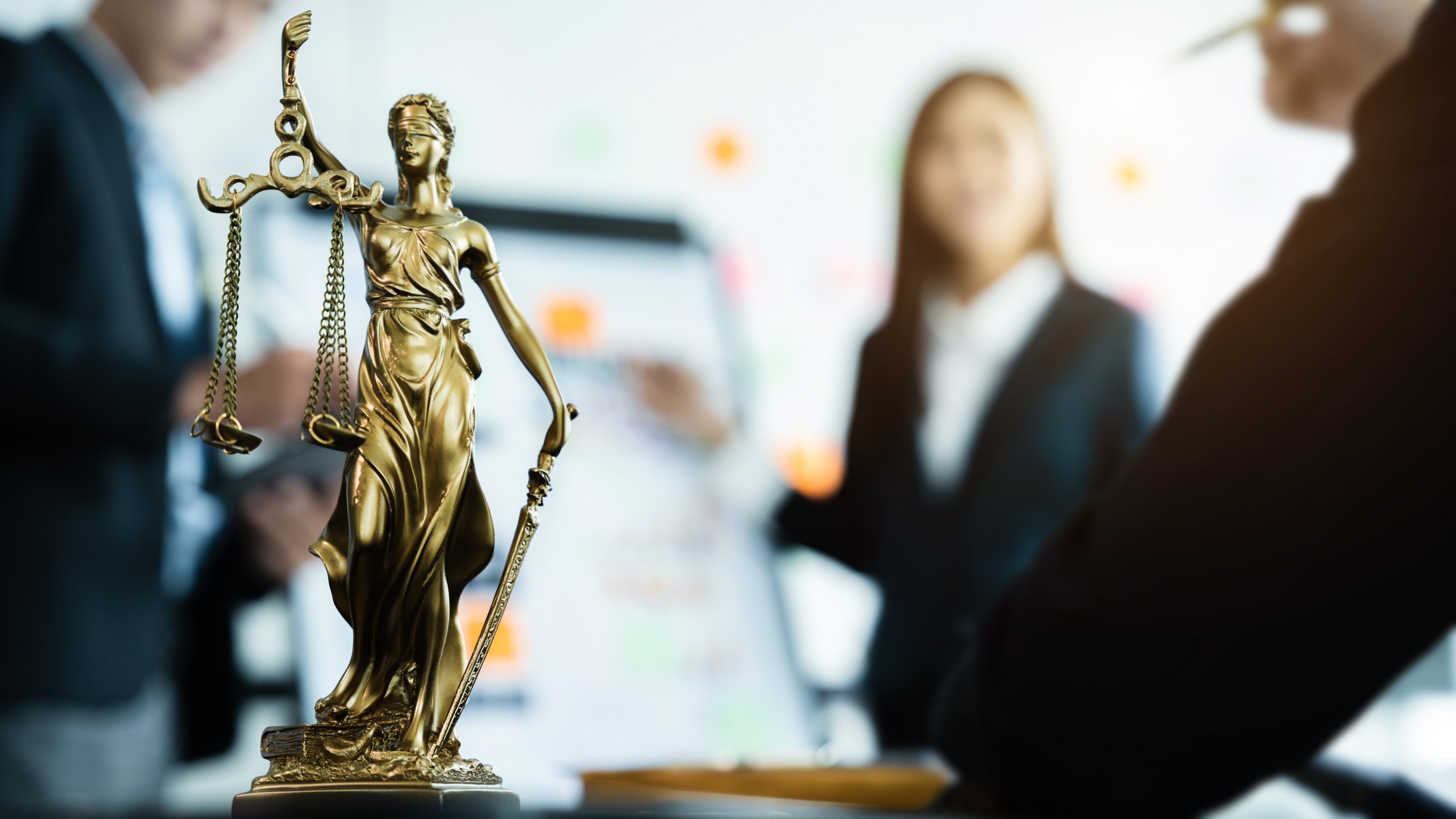 Justice statue beside legal team meeting